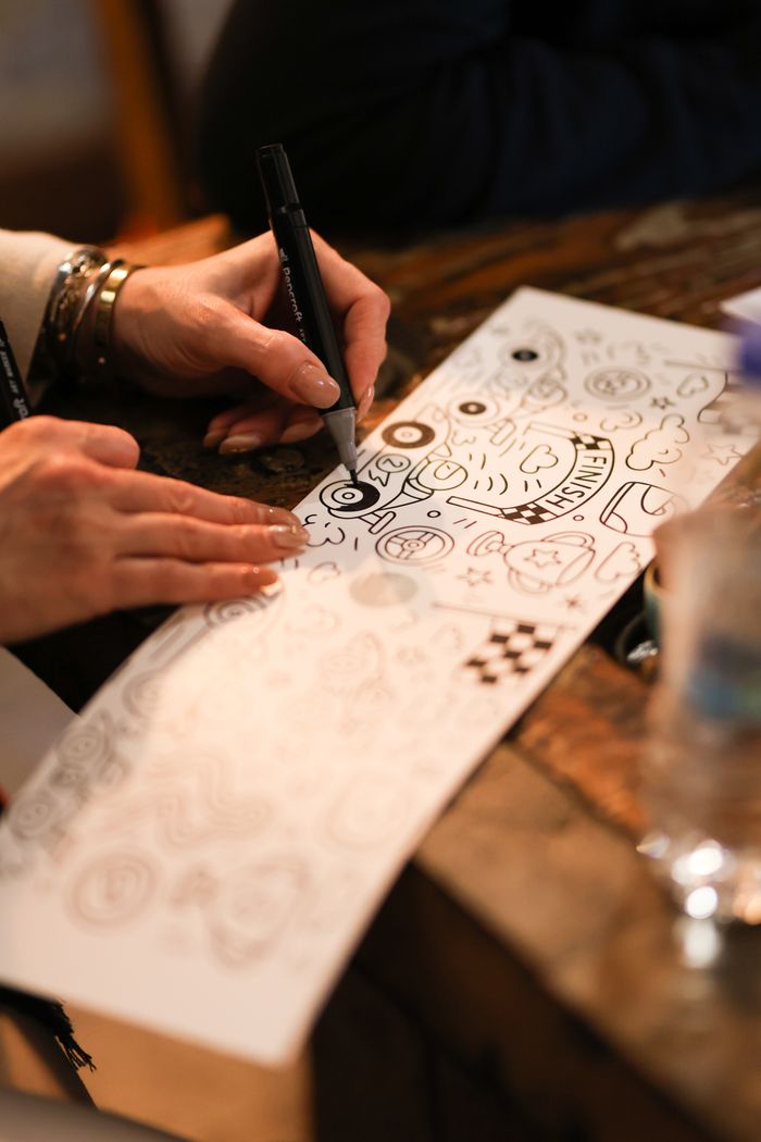 Close-up of hands drawing on paper in an artistic workshop setting, emphasizing creativity.